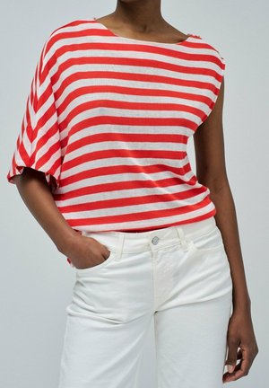Haut à manches courtes rayé rouge et blanc avec un col bateau, fabriqué en tissu doux. Associé à un pantalon blanc, mettant en valeur un look décontracté.