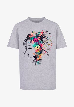 Bambino con t-shirt grigia con stampa floreale colorata sul volto, pantaloni cargo color oliva e scarpe da ginnastica bianche, in piedi con le gambe divaricate.