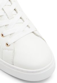 Hvide lædersneakers med hvide snørebånd og gyldne metaljern. Glat overflade og rund tå. Sidelinjen har subtile syninger.