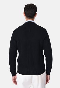 Maglione a coste navy con colletto alto, maniche lunghe e tessuto testurizzato. Presenta una forma dritta e una finitura minimale.