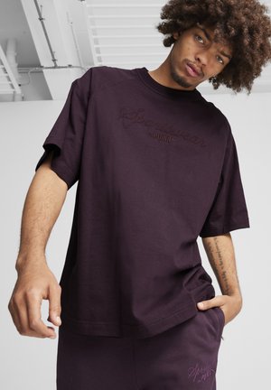 Tamnosmeđi oversized majica od pamuka, s uzdignutim logotipom "Sportswear by PUMA". Kratki rukavi i opušteni kroj s glatkom teksturom.