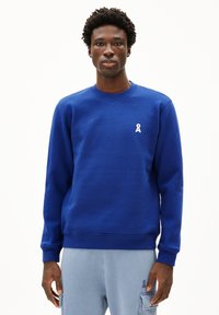 Blauwe katoenen sweatshirt met een ronde hals, ribgebreide mouwen en een klein wit lintlogo op de borst. Glad textuur, casual ontwerp.