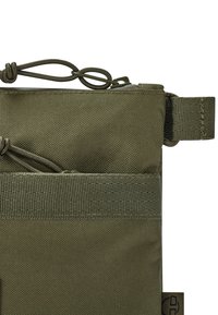 Sacca in nylon verde oliva con superficie strutturata, dotata di chiusura a cordoncino e di un anello per il fissaggio. Include un dettaglio con tasca piatta.