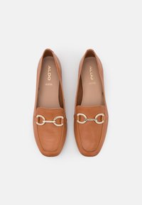 Paire de mocassins en cuir marron avec détail mors doré et bout carré, marque ALDO sur la semelle intérieure.