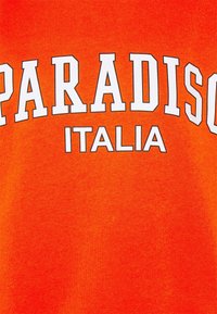 Oranžové bavlněné tričko s nápisem "PARADISO" vytištěným tučnými bílými písmeny nad "ITALIA" v menším textu. Hladká textura, ležérní design.