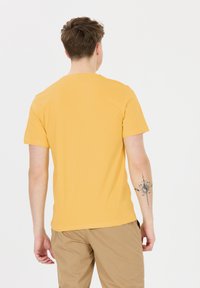 Kortärmad t-shirt med rund hals i klar gul bomull. Har en slät textur och en enkel design utan synliga logotyper eller mönster.