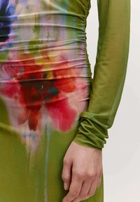 Grünes Kleid mit gerafftem Design, das mit einem bunten Blumendruck in Rot, Pink und Blau versehen ist, gefertigt aus einem glatten, leichten Stoff.