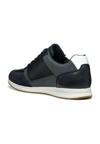 Zapatilla con una mezcla de cuero azul oscuro y gris, un acabado texturizado, acento en el talón blanco y suela de goma. Presenta un diseño tradicional de cordones.