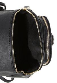 Czarny skórzany plecak z złotymi detalami zamków, posiadający przestronne, niepodszewkowane wnętrze. Projekt obejmuje podwójne zasuwane przegrody dla lepszej organizacji.