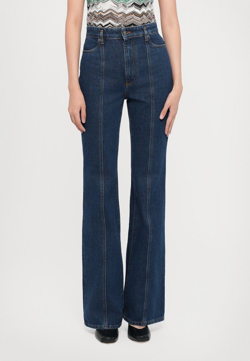 Jean taille haute bleu foncé avec des jambes larges, présentant des poches avant et arrière, des coutures visibles et une texture en denim lisse.