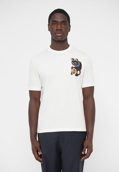 Λευκό βαμβακερό μπλουζάκι με γραφικό μαύρης γάτας με πολύχρωμες λεπτομέρειες στο αριστερό στήθος. Κοντά μανίκια και στρογγυλή λαιμόκοψη.