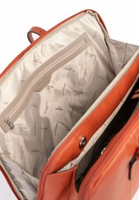 Borsa a tracolla in pelle arancione aperta per mostrare l'interno in tessuto beige con motivo del logo Hexagona Paris e una tasca interna con zip.