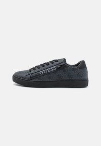 Tenis cu nuanțe de negru și gri, realizat dintr-un material texturat și piele, cu un design cu șireturi negre și cu inscripția "GUESS" pe lateral.