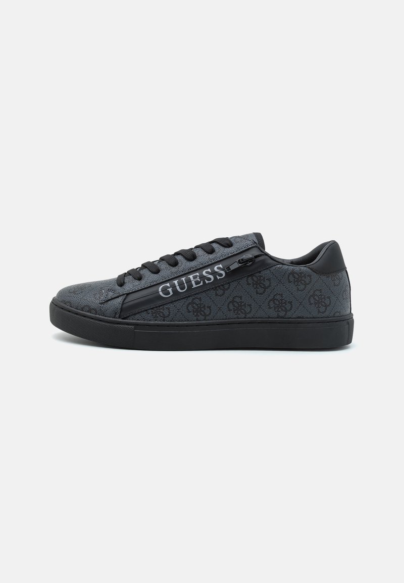 Tenis cu nuanțe de negru și gri, realizat dintr-un material texturat și piele, cu un design cu șireturi negre și cu inscripția "GUESS" pe lateral.