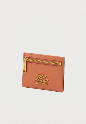 Cardholder made of smooth, burnt orange leather featuring a gold zip pocket and embossed logo design, with neat stitching along the edges.