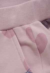 Lys pink beklædning med en ribbet talje. Har abstrakte mønstre i varierende nuancer af pink og blå samt pæne sømme langs sømmene.