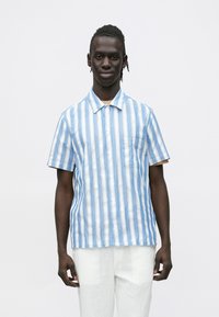 Īsroku krekls ar pogām, gaiši zilu un balti sv�ītrains, izgatavots no lina, ar krūšu kabatu un apkakli.