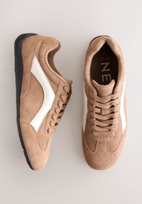 Baskets en daim marron avec une bande latérale blanche. Dessus texturé, bout rond et semelle extérieure en caoutchouc noir. Dotées de lacets et d'un col rembourré.