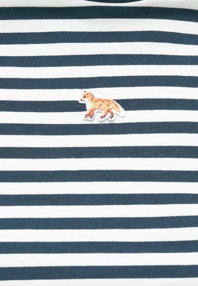 Námornícky a biely pruhovaný tričko s vyšitým oranžovým líškom na ľavej strane hrude. Tkanina sa zdá byť mäkká s rebrovaným golierom.