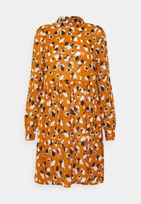Oranssi mekko, jossa on mustavalkoinen kukkakuosi. Pitkät hihat, kauluskietaisukaulus ja virtaava hame. Valmistettu kevyestä kankaasta.