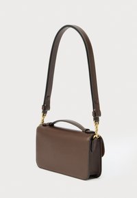 Sac à main en cuir marron avec poignée supérieure et bandoulière amovible avec fermoirs dorés sur fond blanc.