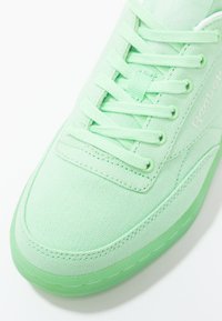 Ljusgrön kanvas sneaker med matchande snören, texturerad ovandel, gummisula och subtil branding på sidan.