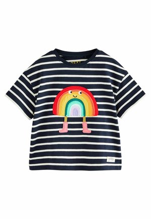 T-shirt à manches courtes rayé bleu marine et blanc, avec un patch arc-en-ciel multicolore représentant un visage souriant et des bottes roses sur un corps arrondi.