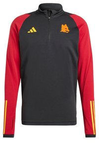 Top deportivo con cremallera que presenta un cuerpo negro, mangas rojas y un logo de lobo naranja. Rayas de Adidas en amarillo en las mangas. Tejido suave y flexible.