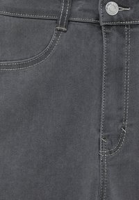 Gros plan sur un jean en denim gris montrant la poche avant, la passants de ceinture, les coutures des coutures, et un bouton métallique avec le nom de la marque gravé.