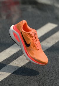 Nike-Laufschuh in leuchtendem Orange mit schwarzem Swoosh, Obermaterial aus Mesh, gepolstertem Zwischensohle und weißer Außensohle. Leichtes Design mit strukturierten Details.