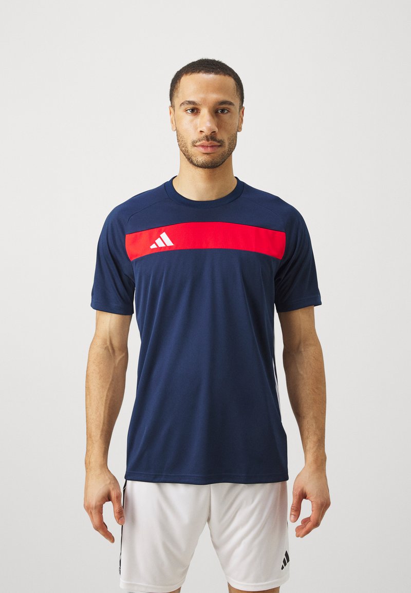 Navy short-sleeve athletic shirt with a red horizontal stripe across the chest, featuring three white stripes and logo detail.