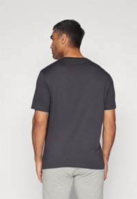 Grå bomulds t-shirt med rund hals og korte �ærmer, vist fra ryggen. Glat tekstur, tætsiddende design, minimalistisk stil.