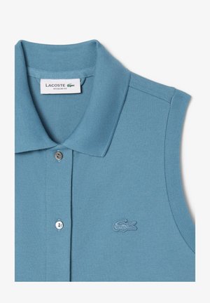 Polo en bleu clair, sans manches, avec un tissu texturé. Doté d'un col, d'une fermeture à boutons et d'un logo brodé sur la poitrine.