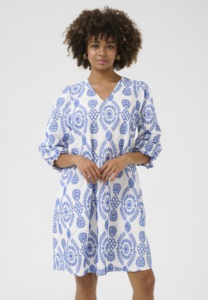 Witte tuniekjurk met opvallende blauwe bloemmotieven, V-halslijn en driekwart mouwen. Gemaakt van lichtgewicht stof met een relaxte pasvorm.