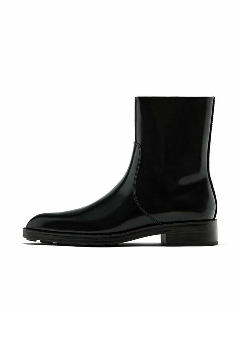 Botte noire en cuir mi-mollet avec bout arrondi, talon bas empilé, et fermeture éclair latérale, présentée sur un fond blanc.