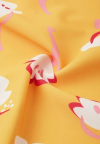 Gelber Stoff mit abstrakten Blumenmustern in Pink und Weiß, mit glatter Textur und leichtem Glanz, in Wellen gerafft.
