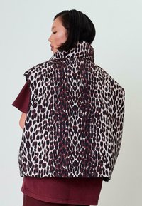 Gepolsterte Weste im Leopardenmuster mit hohem Kragen, überwiegend in Creme- und Dunkelrot-Tönen, mit einer lässigen, oversized Silhouette.