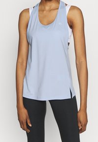 Débardeur de sport bleu clair avec un col rond plongeant, des fentes sur les côtés et un logo sur la poitrine. Confectionné dans un tissu lisse et extensible.