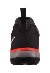 Rear view of a black and gray athletic shoe with a red midsole stripe and a pull tab at the heel.