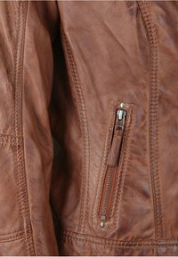 Braune Lederjacke mit einer strukturierten Oberfläche, diagonaler Reißverschlusstasche an der Seite und dezenten Nähdetails entlang der Nähte.