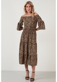 Koffertopp med leopardmønster i brunt og svart, med flagrende ermer, samlet midje og lagdelt skjørtdesign.