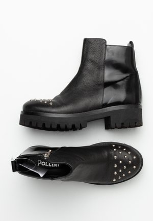 Schwarze Stiefeletten aus einer Mischung aus strukturiertem Leder und glänzenden Einsätzen, mit silbernen Nieten an der Spitze und einer grob profilierten, klobigen Sohle.