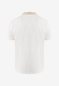 Polo bianca a maniche corte con colletto beige e polsini bianchi, vista da dietro su sfondo semplice.