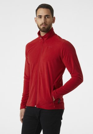 Chaqueta de forro polar roja con un collar alto, cremallera completa y bolsillos laterales. Presenta mangas texturizadas y detalles de logo en el pecho.