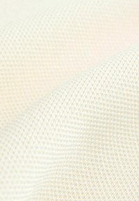 Tessuto di cotone di un color crema chiaro, con una texture a fine griglia. Il materiale appare morbido e leggermente traslucido.