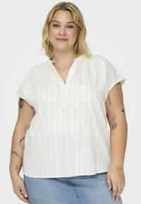 Blusa blanca de manga corta con rayas verticales naranjas, escote en V y ajuste relajado, combinada con jeans de mezclilla claros.