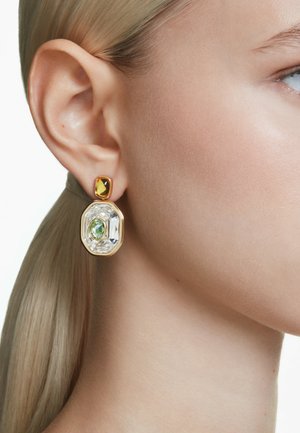 Pendientes en tono dorado que presentan una gran piedra rectangular transparente, una piedra ovalada verde y una pequeña piedra cuadrada ámbar en la parte superior.