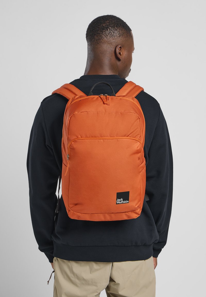Sac à dos orange au design simple, en tissu, doté d'une poche avant zippée, de bretelles réglables et d'un patch logo.