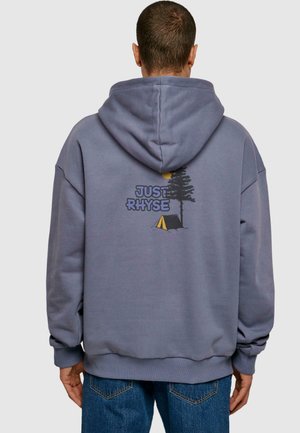 Grey oversized hoodie with a drawstring, featuring a graphic of a tree and tent, and the text "JUST RHYSE" printed on the back.