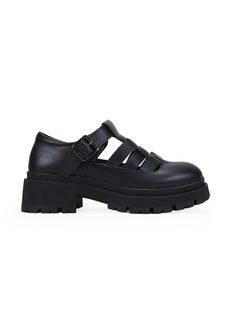 Zapatos de plataforma de cuero negro con puntera redonda, diseño recortado y correa ajustable con hebilla. Suela de goma texturizada con patrón estriado.